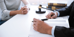 A woman sitting across from a lawyer going over paperwork.